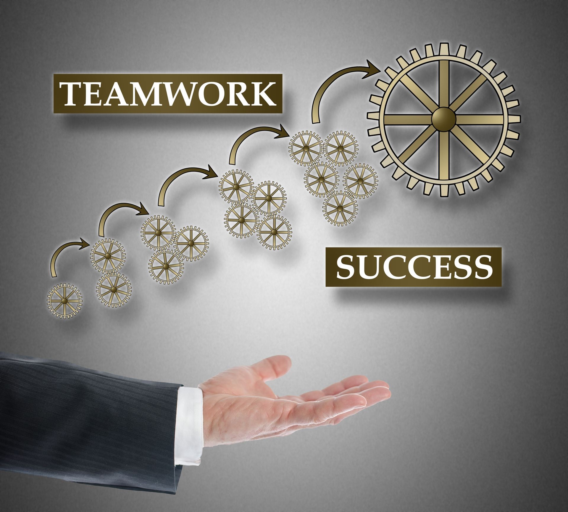 Teamwork success concept levitating above a hand on grey background Teamwork success concept levitating above a hand on grey background